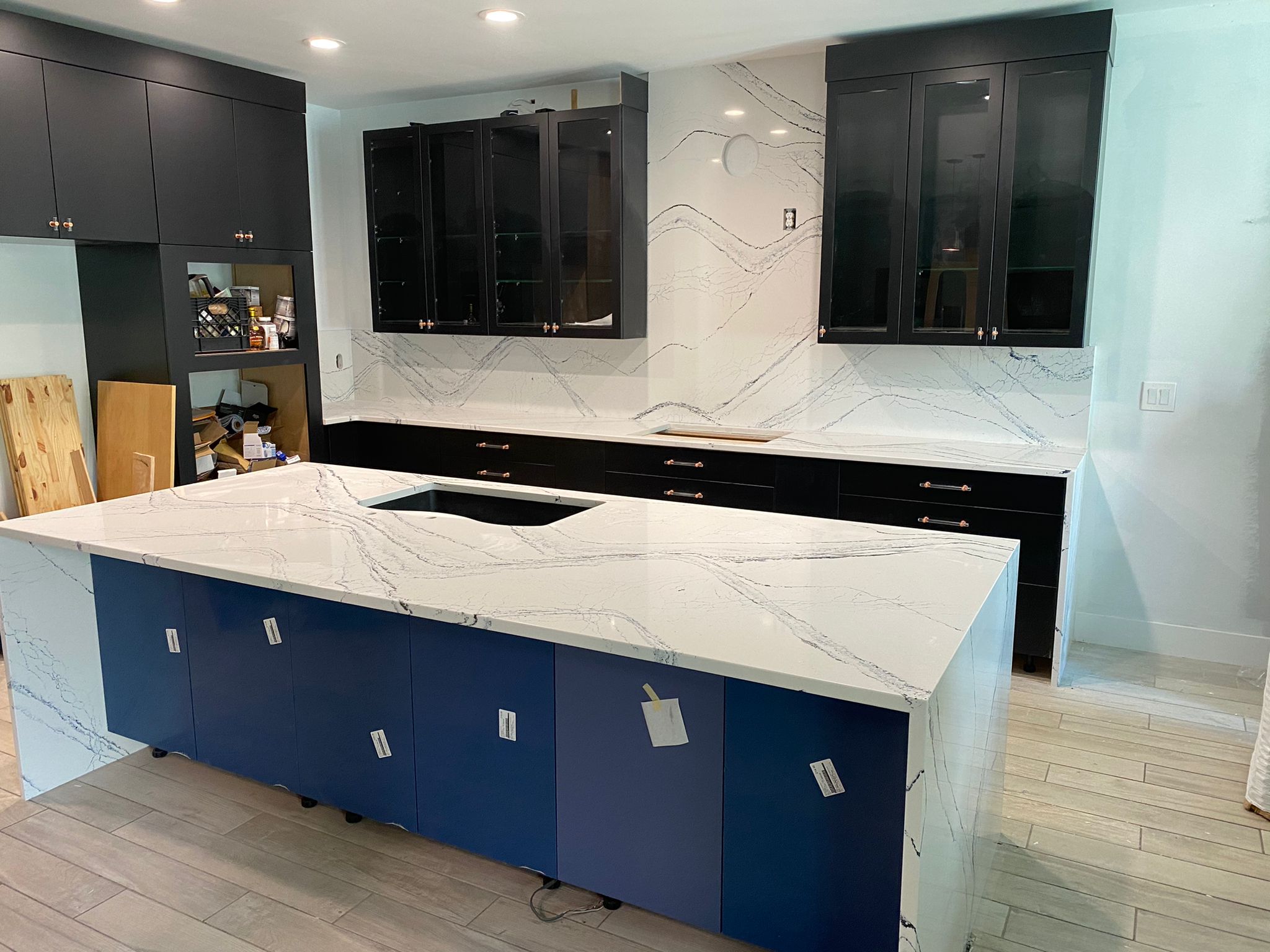 Modern kitchen with black and blue cabinets and white marble countertops